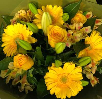 Rise & Shine - A bouquet bursting with cheerful energy, dominated by sunny yellow tones, featuring:
• 	Yellow gerberas with large, bold petals that add a playful touch.
• 	Yellow roses, symbolising friendship and joy, nestled gracefully among the other blooms.
• 	Alstroemeria flowers in yellow hues, adding delicate contrast and texture.
• 	Lilies in  buds and lush foliage interspersed throughout, giving the bouquet a fresh, vibrant feel.
The flowers are tightly packed, creating a harmonious and eye-catching composition. The overall effect is warm, uplifting, and perfect for brightening any space or mood. This bouquet is like a little burst of sunshine.